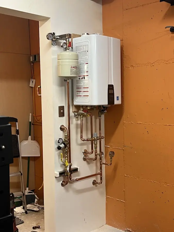 Plumbing technician inspecting water heater connections in East Riverdale